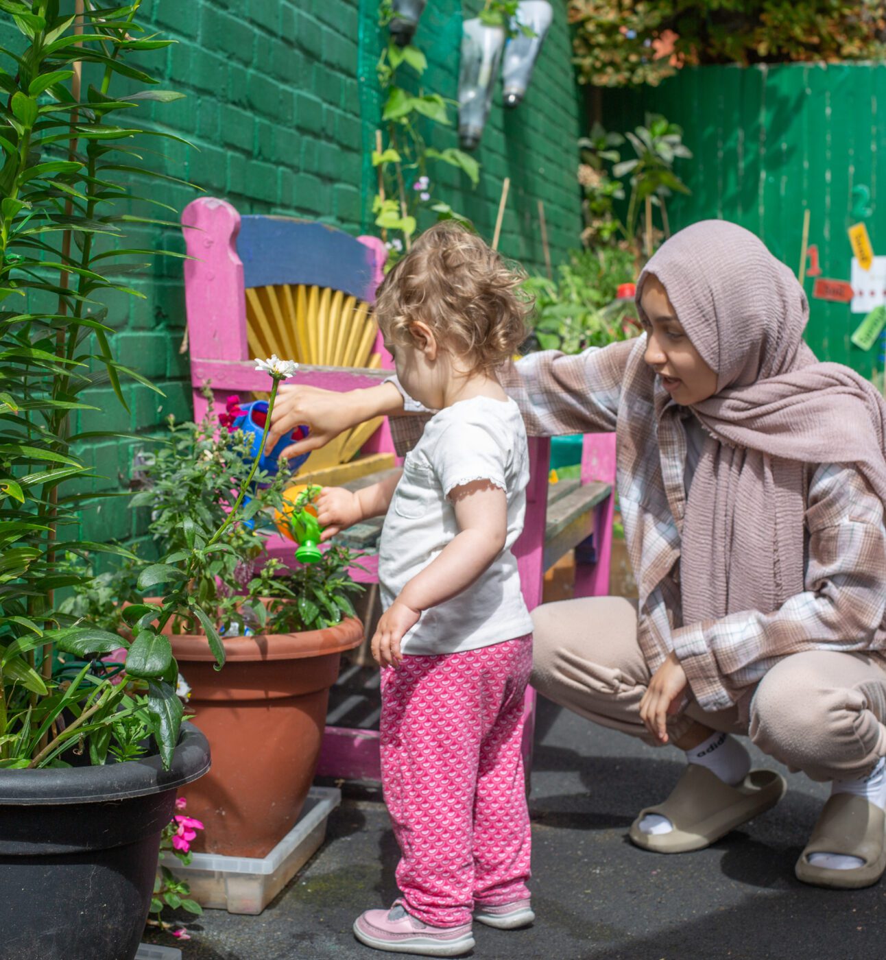 Staff helping a child water a plant