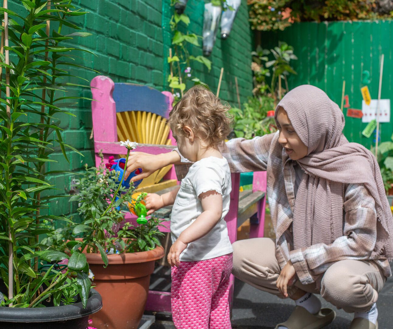 staff helping child water plant