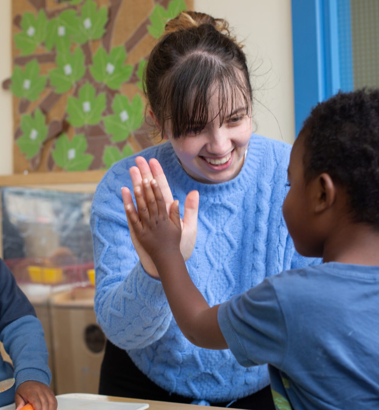 Photo of staff member high-fiving a child