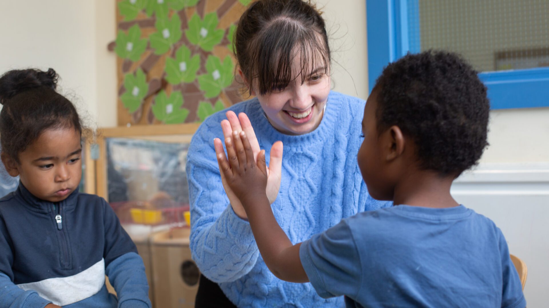 Photo of staff member high-fiving a child