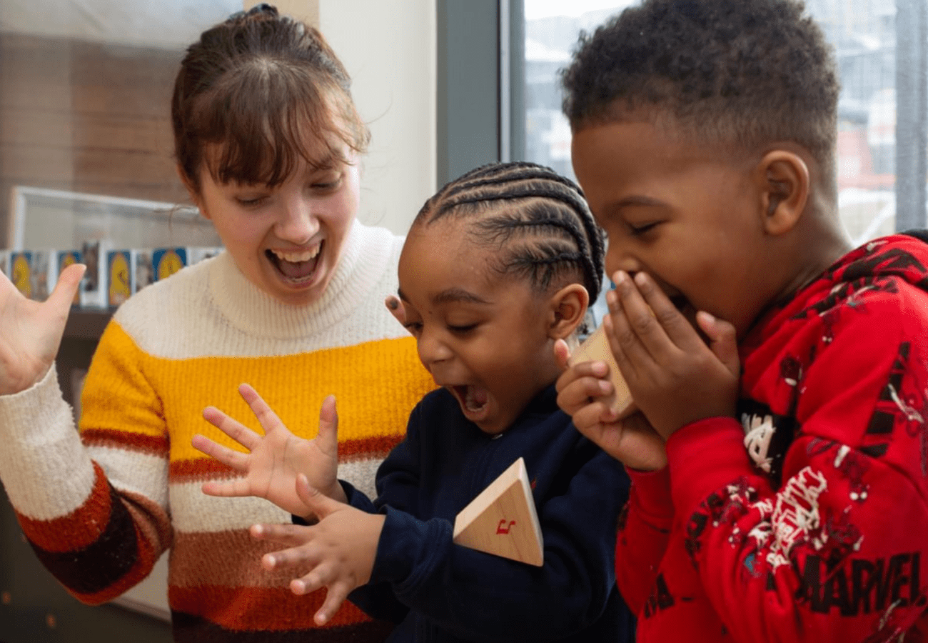Photo of teacher with two children playing a game