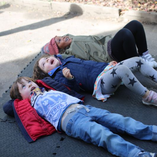 staff and children outside playing through foams into a box