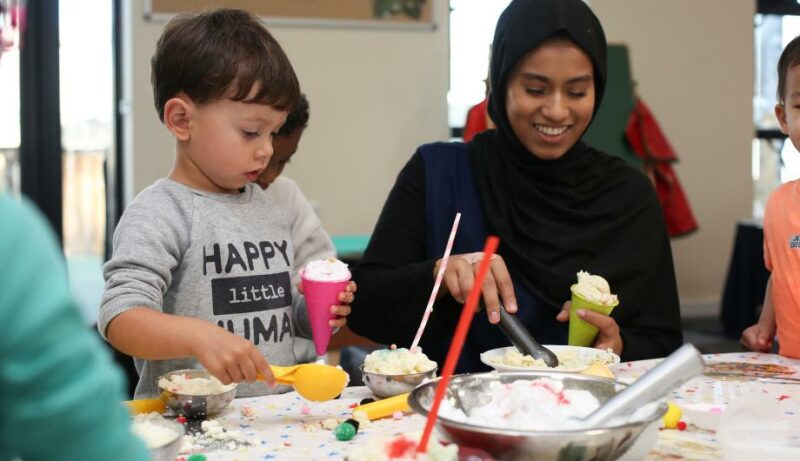 Staff making ice cream cones with child