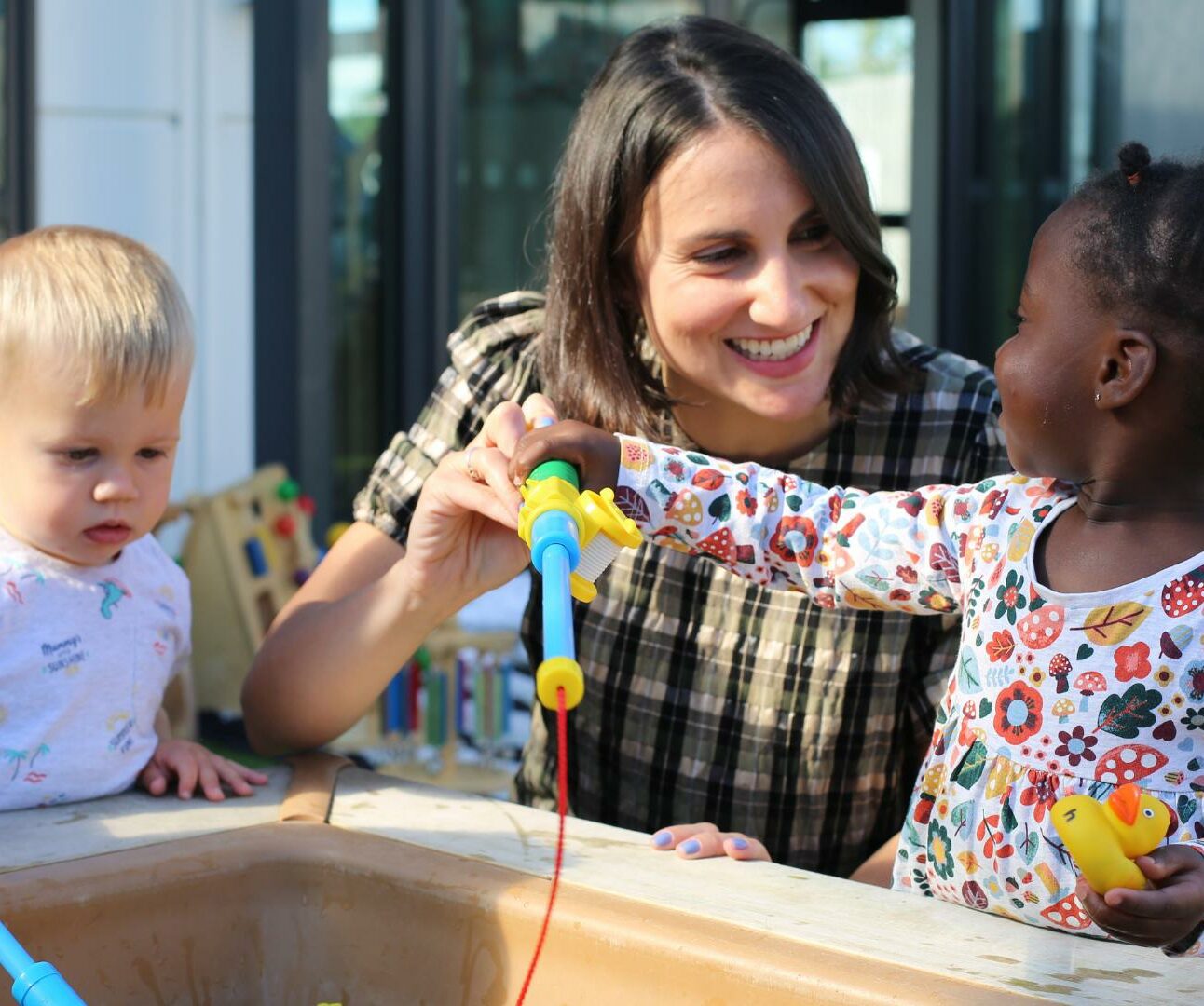 Staff member with two children playing in the garden