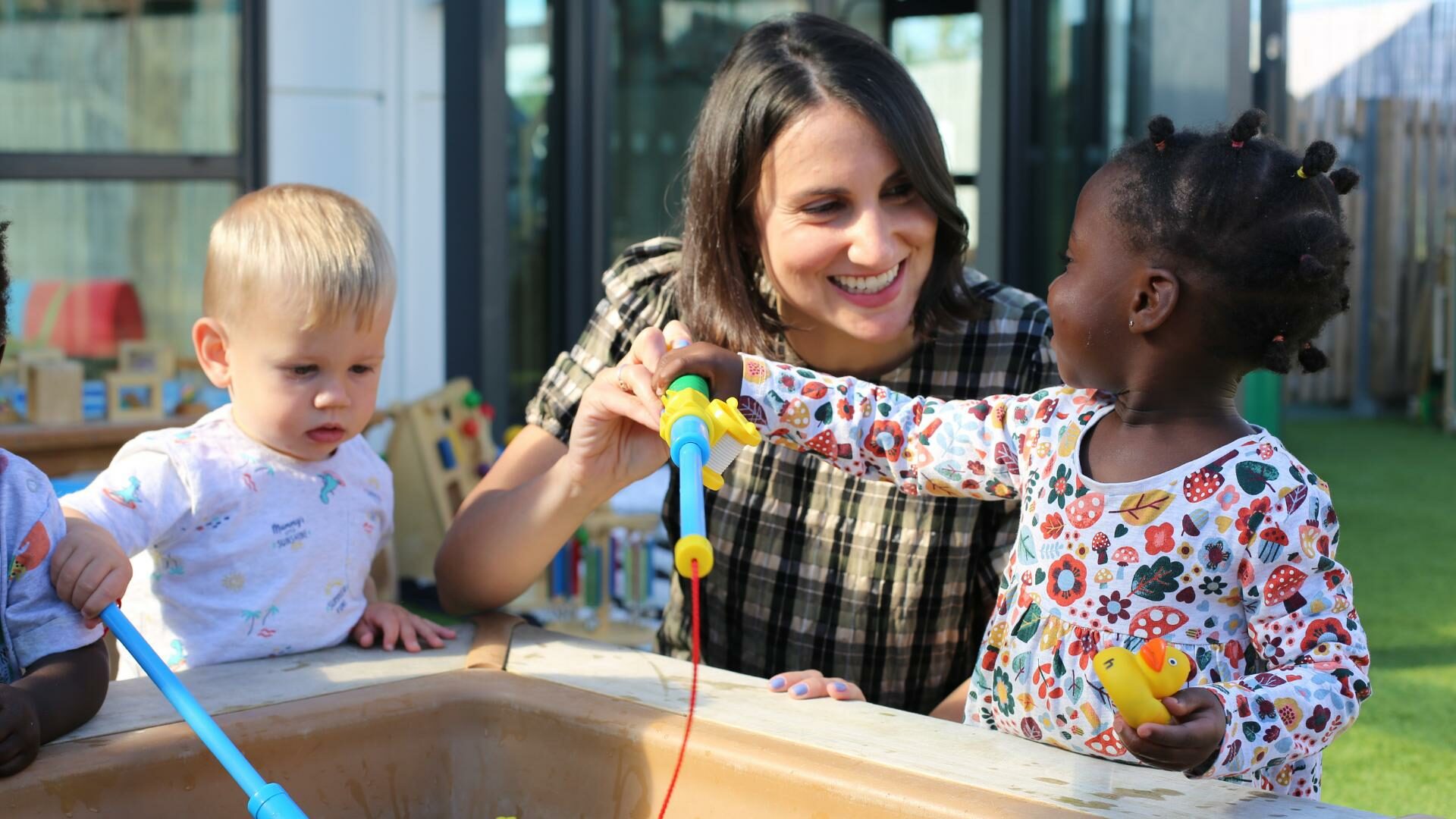 Staff member with two children playing in the garden
