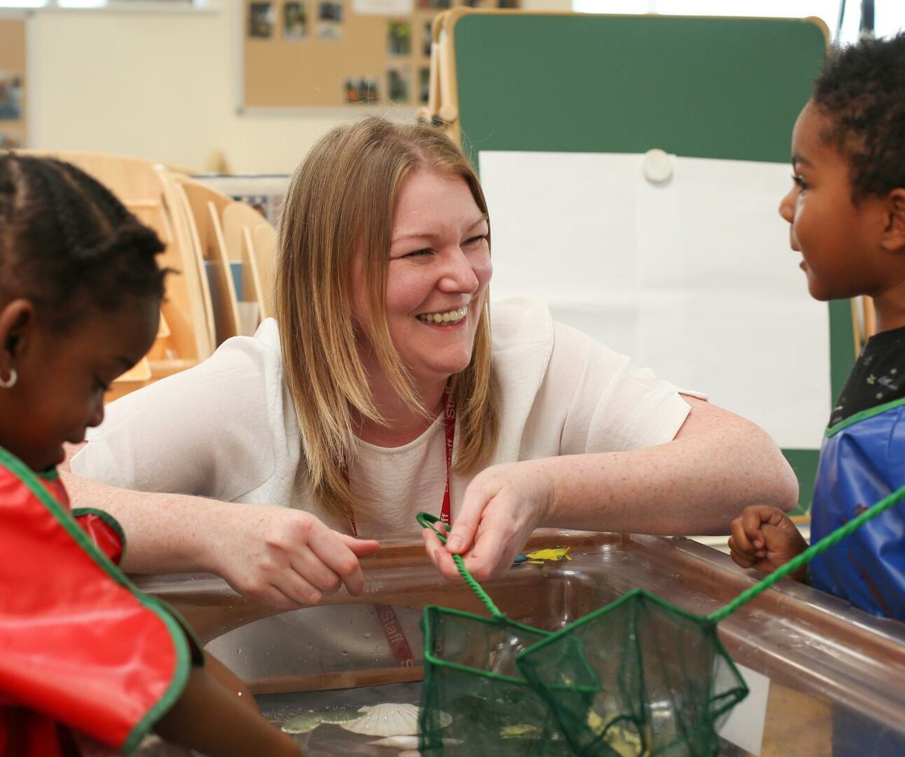 Children and staff member playing with fishing nets