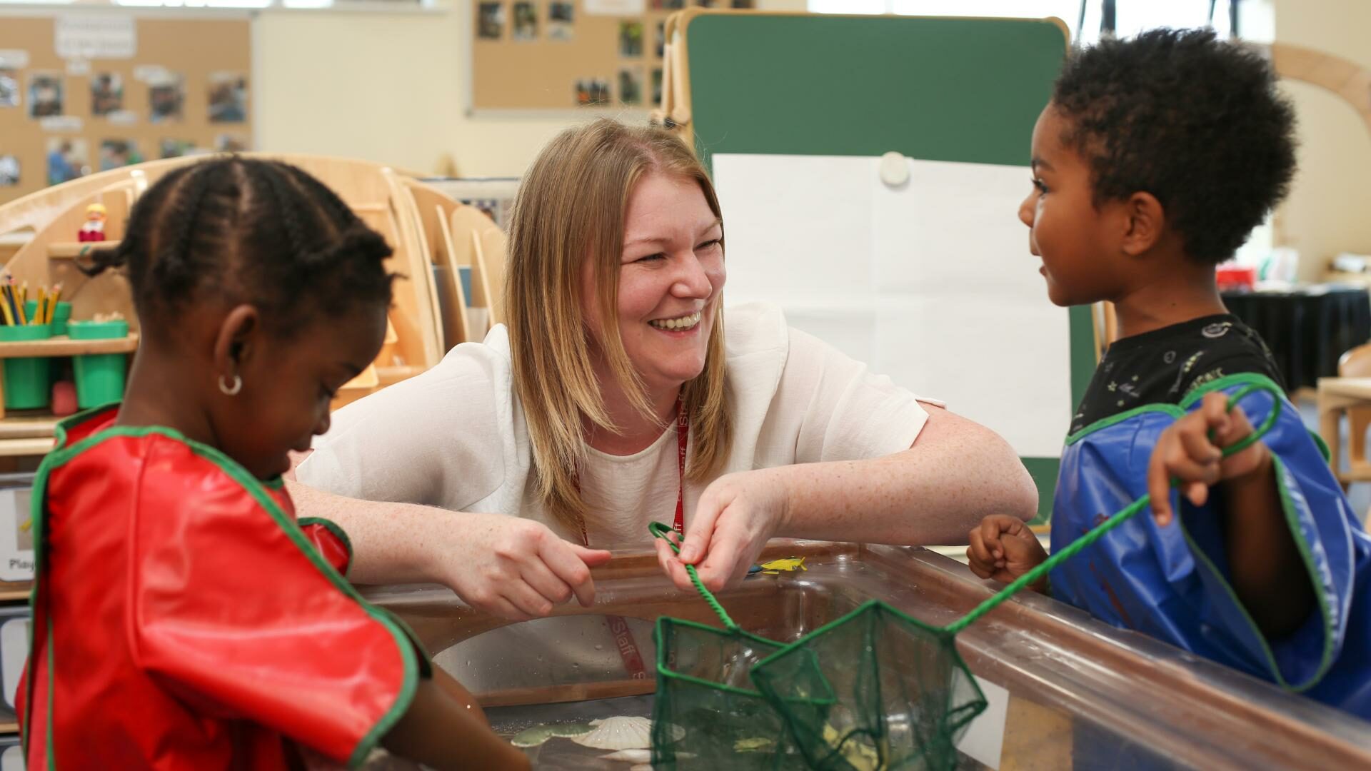 Children and staff member playing with fishing nets