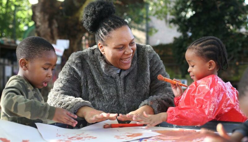 staff and two children outdoors painting