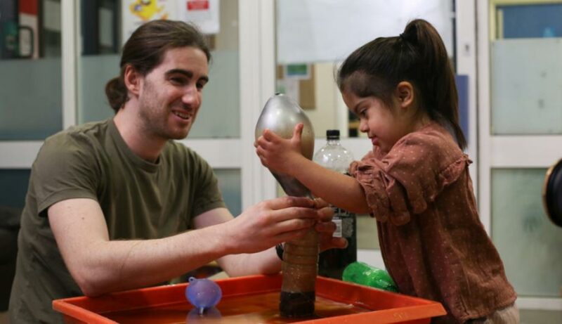 male staff and child doing a science experiment with balloon