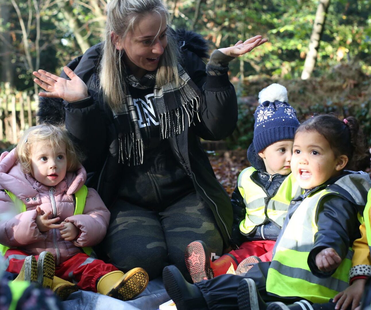 Staff and a group of children sitting down at their local park engaging in an activity.