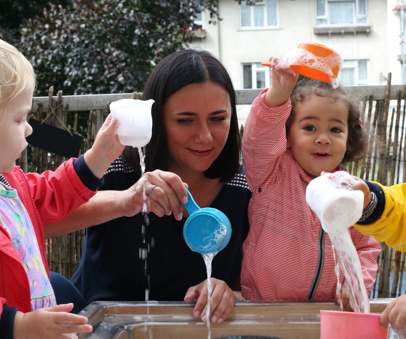 Staff and children playing with water and cups