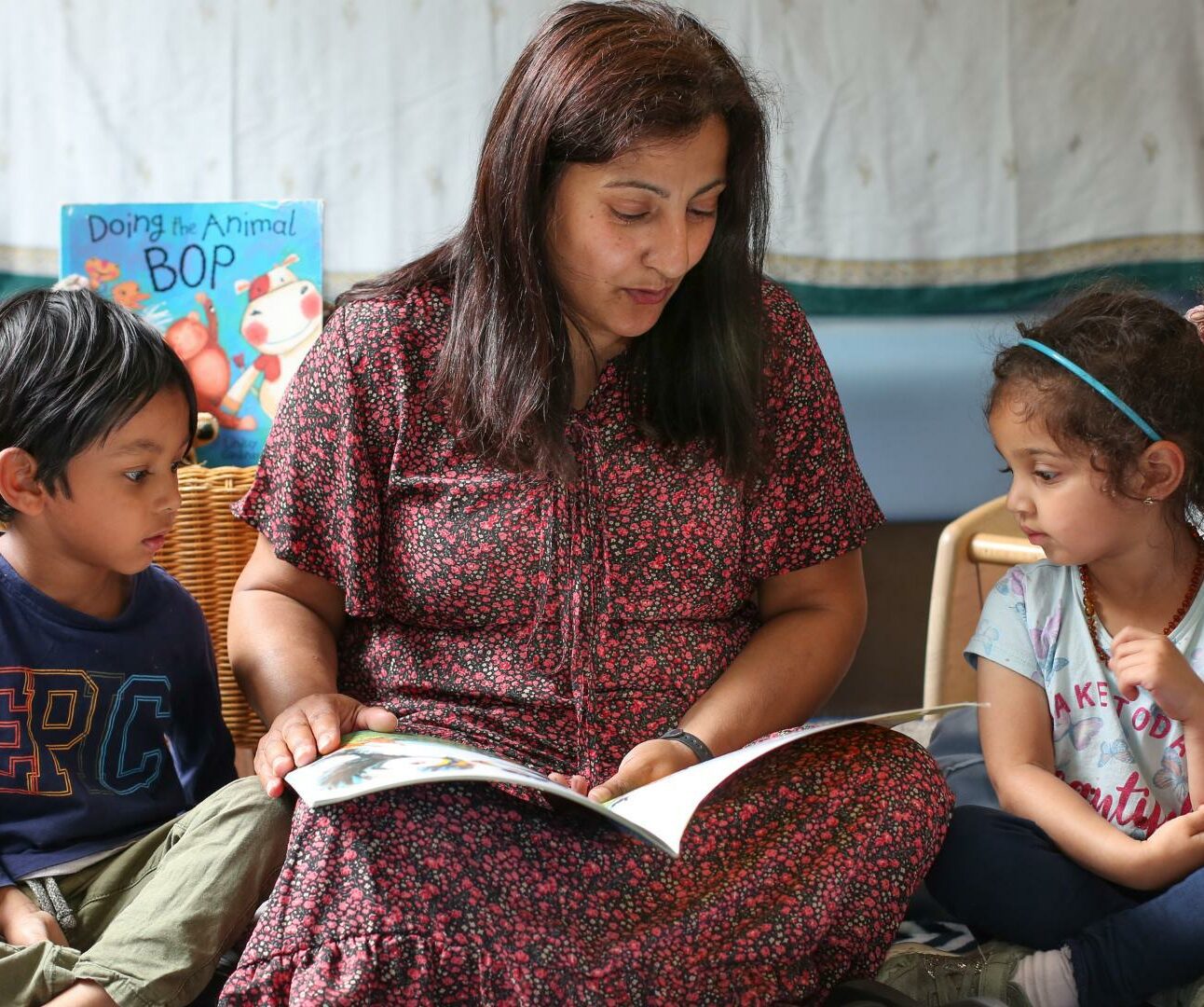 staff and children sitting on the carpet reading a book