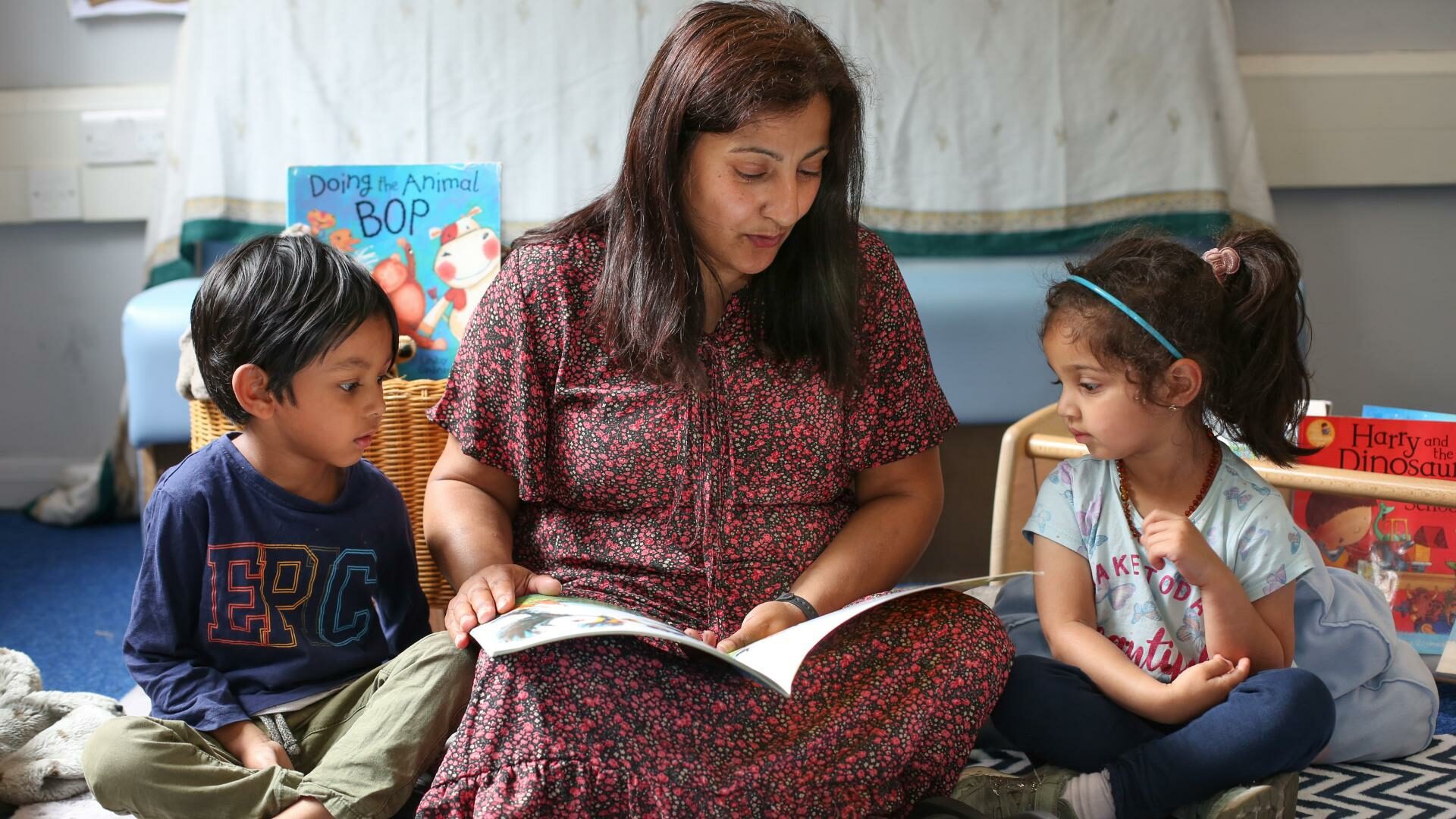 staff and children sitting on the carpet reading a book