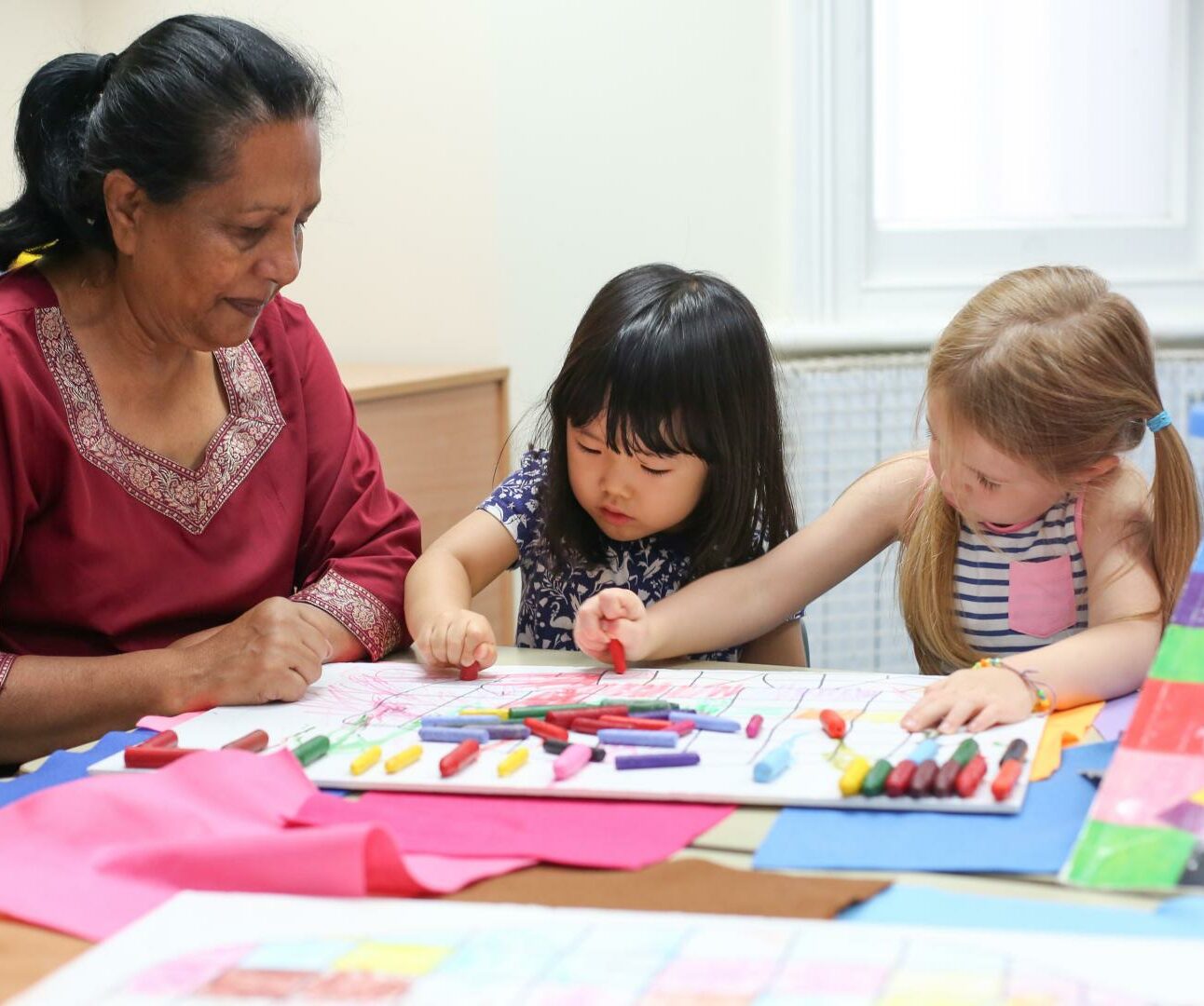 Staff and child using crayons to draw