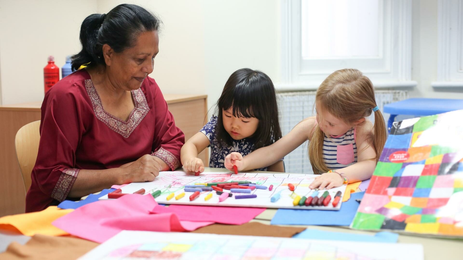 Staff and child using crayons to draw