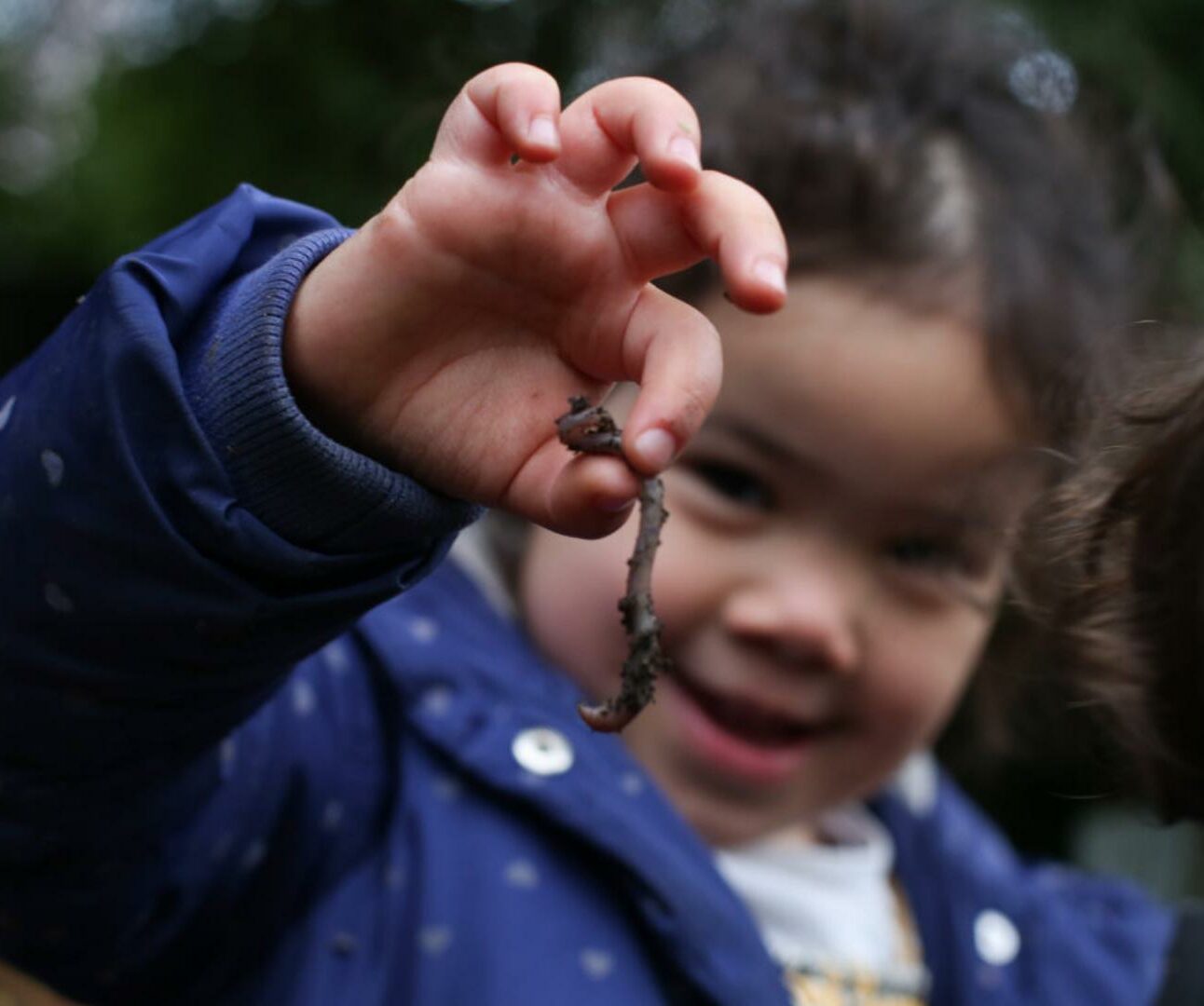 Girl holding up a worm from the nursery wormery