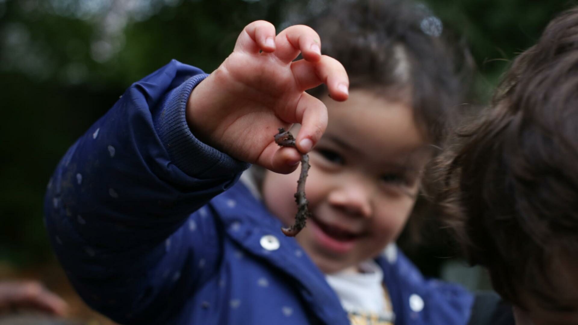 Girl holding up a worm from the nursery wormery