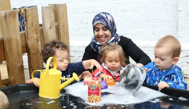 Staff and children enjoying water play outside in the garden