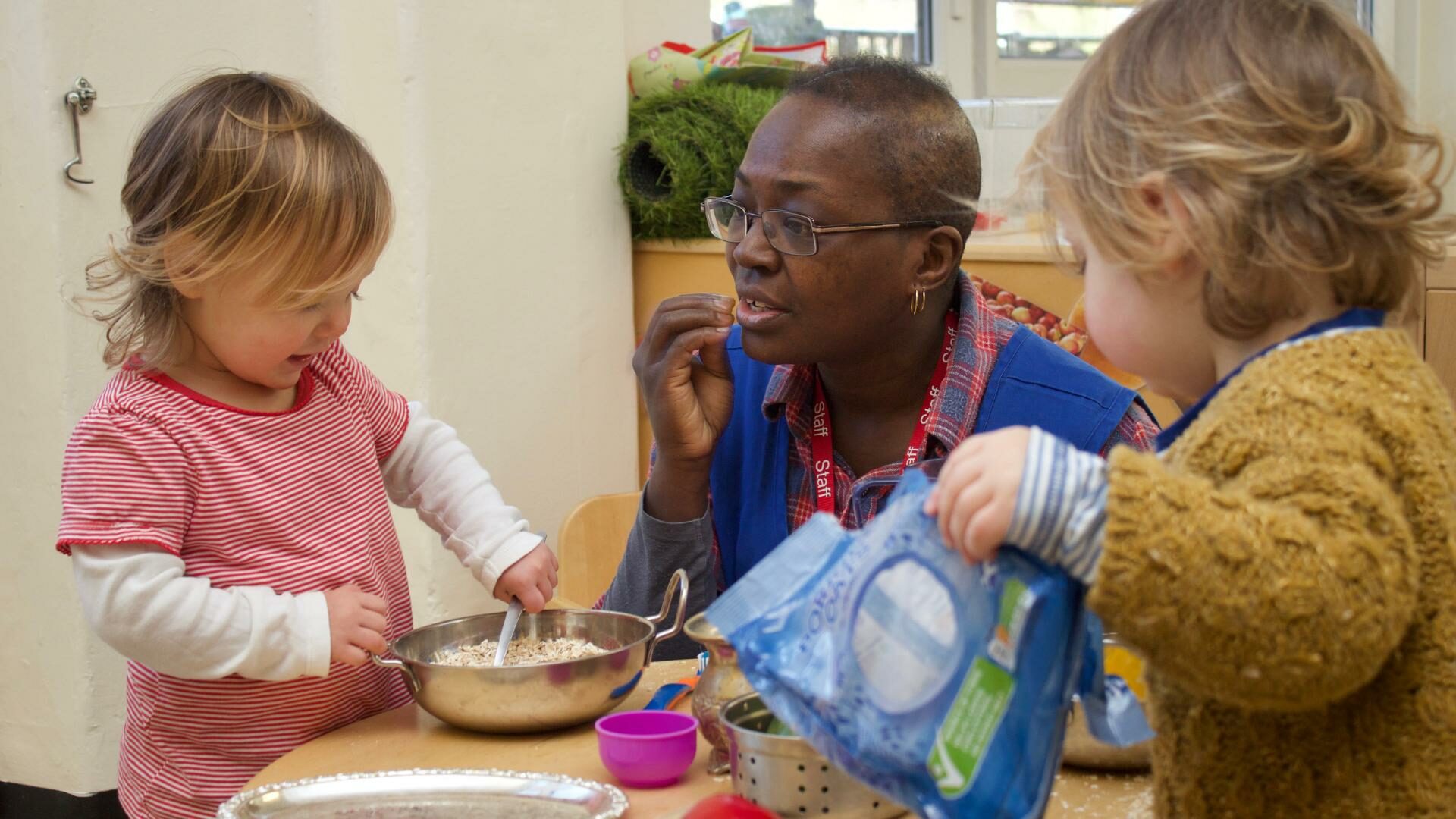 Staff using makaton/sign language with toddler in the home corner