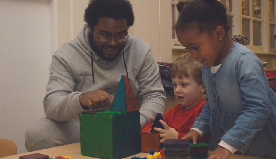 male staff doing a building activity with children