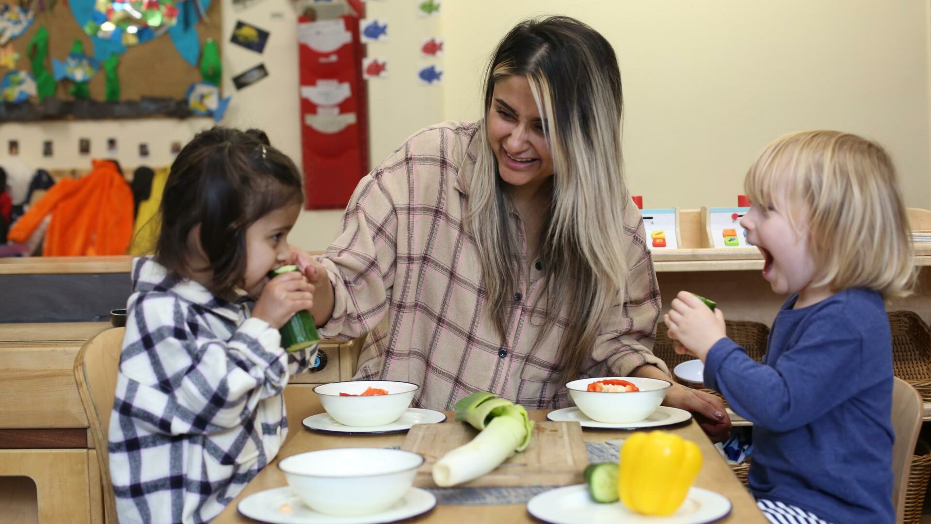 staff and children in the home corner cutting up vegetables