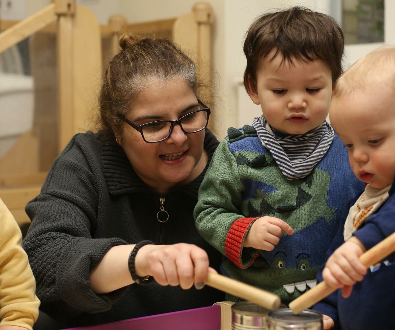 Staff teaching a baby to hit the drums.