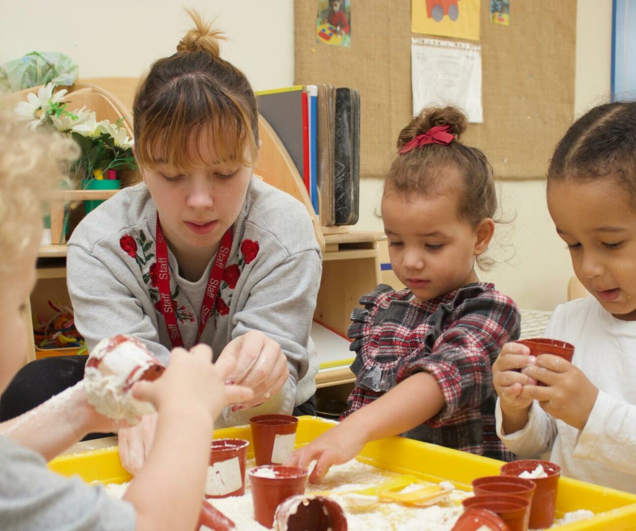 staff and children getting stuck into messy play using small flower pots and a slimy consistency