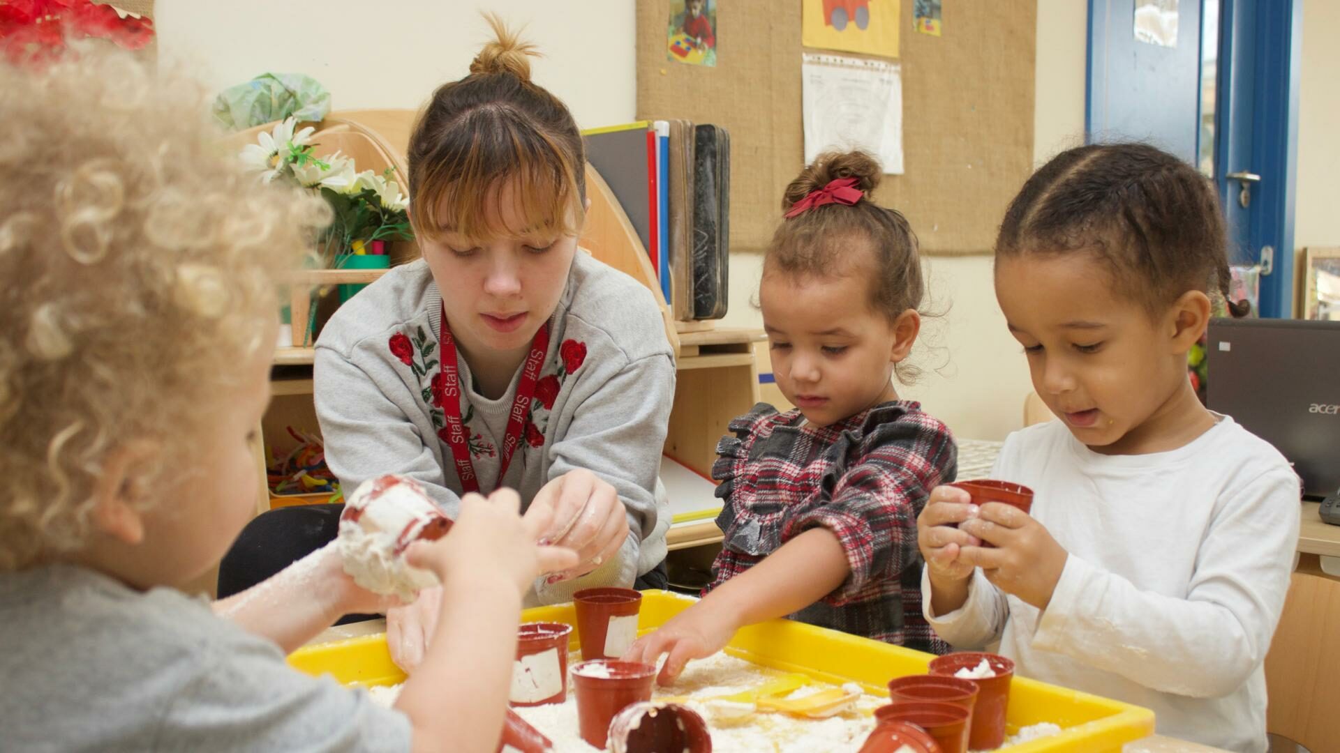 staff and children getting stuck into messy play using small flower pots and a slimy consistency