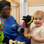 Teacher showing a baby a doll puppet