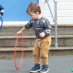 A child trying to spin hoola hoop.