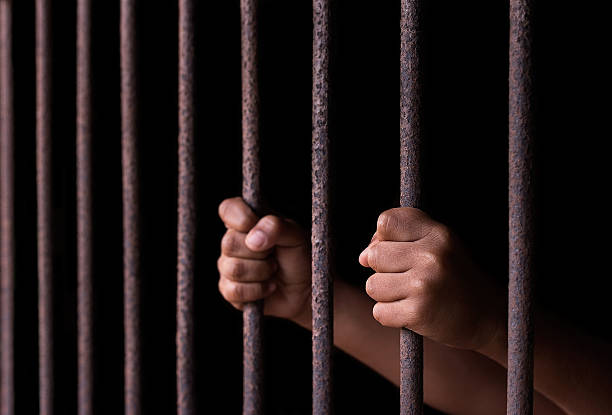 A childs hands holding cage bars