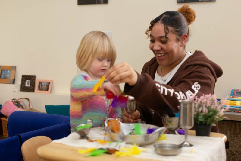 Child and teacher playing with feathers