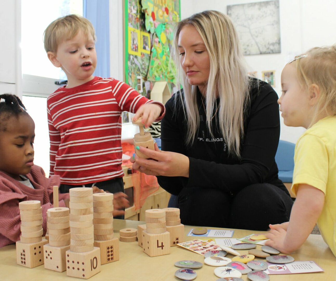 Teacher helping a group of children count with wooden blocks