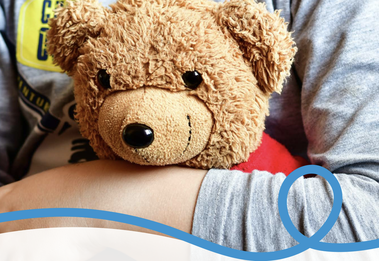 Close up of a teddy held in child's arms