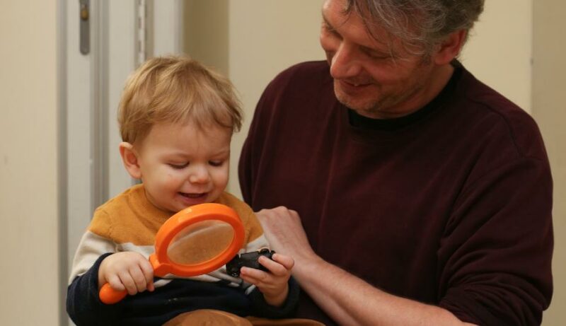 Staff member with a child holding a magnifying glass