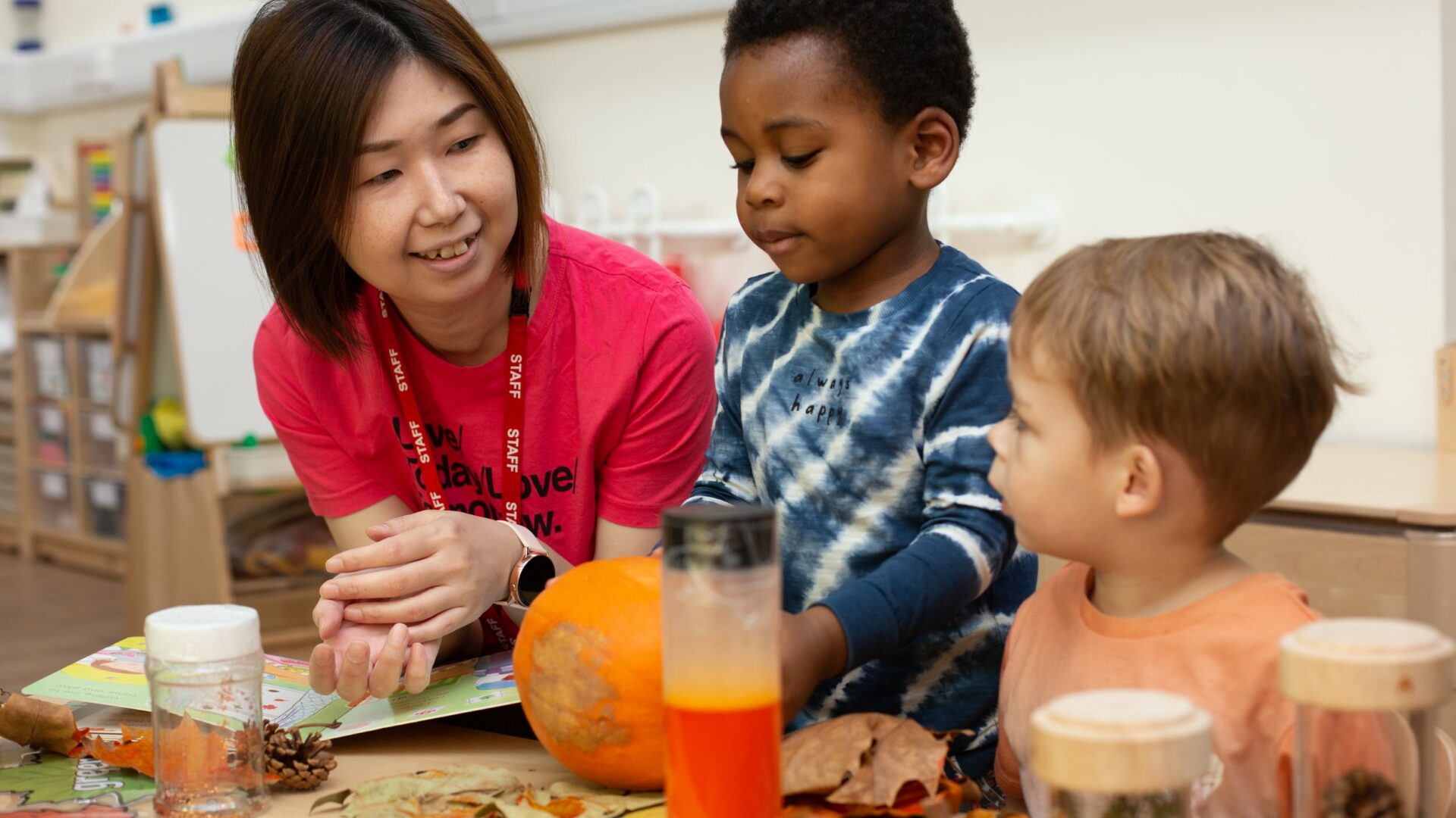 Staff member talking to two children looking at a pumpkin