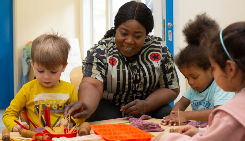 Staff member at Deanery Road helping children play with play dough