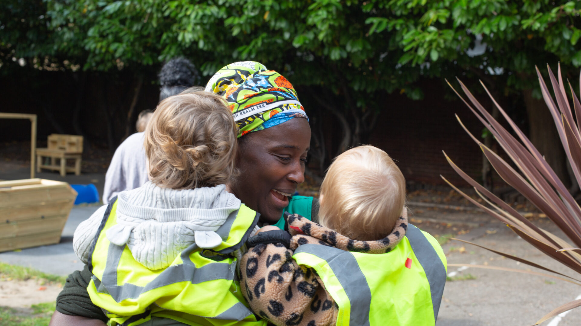 A staff member giving two children a hug