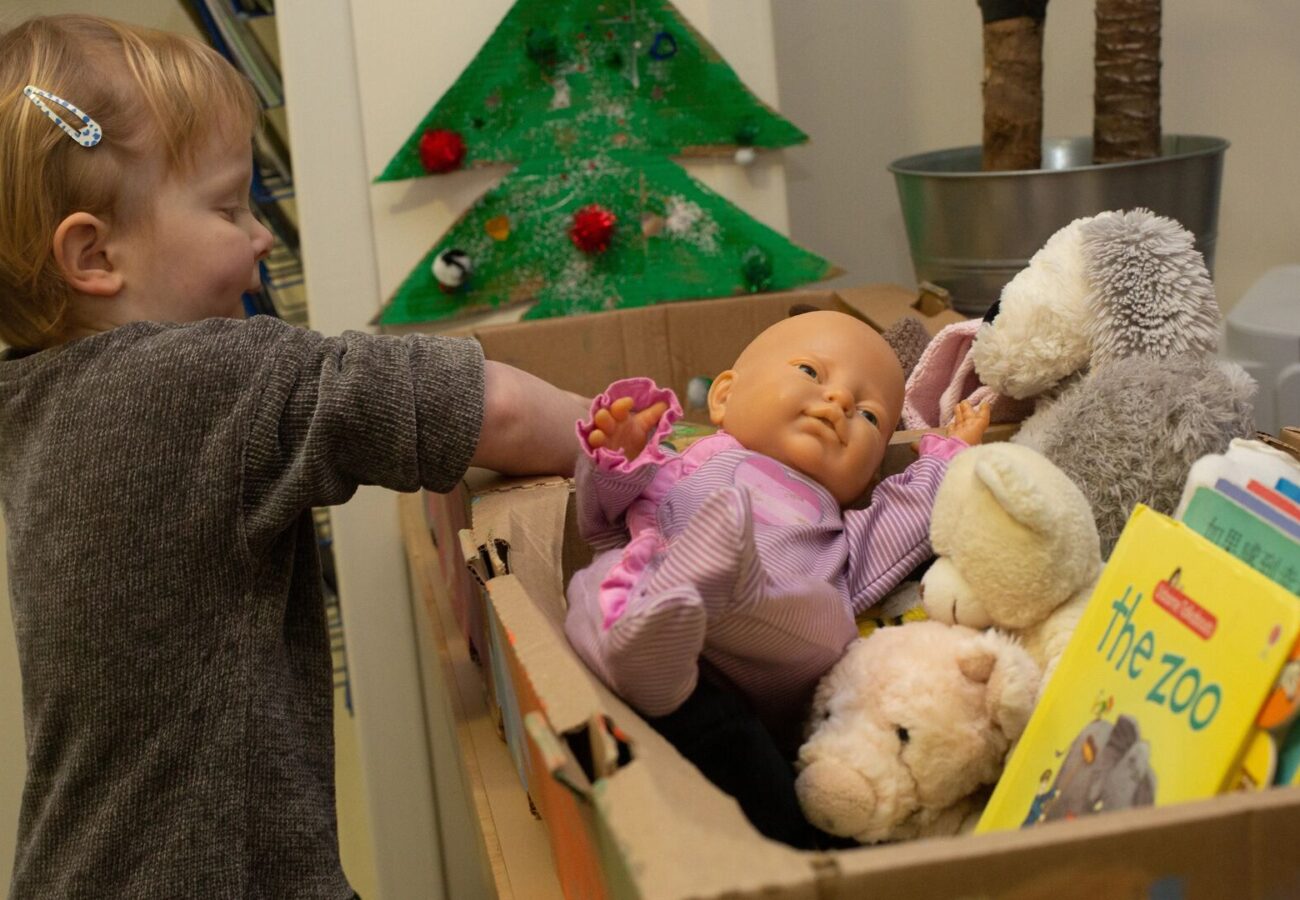 Children at a LEYF nursery putting toys into donation boxes for a local community charity, demonstrating the organisation's commitment to social impact