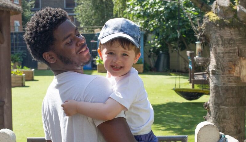 Men in childcare garden portrait with child
